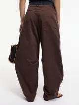 Pantalón slouchy marrón de tiro alto con cierre de botón y cremallera, pretina con pasacinto y rayas blancas laterales.