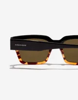 Lentes de sol Hawkers unisex con montura cuadrada negra y carey, y lentes marrones.