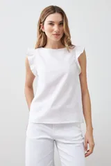 Blusa blanca sin mangas de lino con cuello redondo y volados en los hombros.