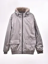 Campera gris con capucha con borde de piel sintética, cierre frontal con cremallera, bolsillos laterales con solapa y bolsillo con cremallera en la manga.