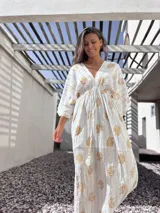 Túnica larga de algodón color blanco con estampado de flores y rayas verticales doradas, escote en V y mangas 3/4.