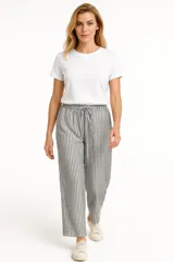 Pantalón de lino color beige, de corte ancho y tiro alto, con bolsillos laterales y cintura elastizada con cordón ajustable.