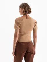 Top corto gris de punto acanalado, con escote redondo, manga corta abullonada y cierre frontal con tres ganchos decorados con piedras.