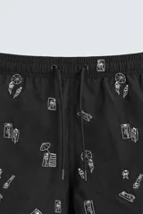 Bañador negro con estampado de dibujos en blanco. Tiene cintura elástica ajustable con cordón, bolsillos laterales y trasero.