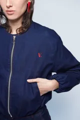 Campera bomber corta de jean azul con cuello a la base, bolsillos ojal, mangas amplias abullonadas y pespuntes en rojo.