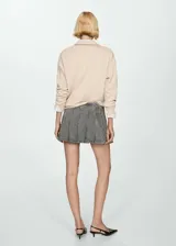 Minifalda gris de jean con diseño de tablas, tiro bajo y cierre lateral con cremallera.