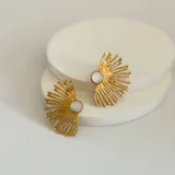 Aros colgantes dorados con forma de sol y centro de nácar.