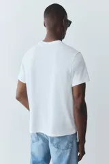 Remera blanca de corte estándar, con cuello redondo ribeteado y bajo recto. Confeccionada con tejido funcional COOLMAX®, una fibra de poliéster de secado rápido que elimina la humedad y regula la temperatura corporal.