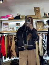 Campera negra de cuero con interior de piel sintética blanca, cierre frontal con cremallera, cuello con solapas y bolsillos laterales.
