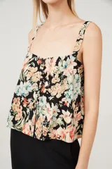 Musculosa con estampado floral multicolor sobre fondo negro, breteles anchos y escote cuadrado.