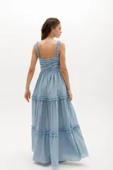 Vestido largo celeste de gasa de algodón con textura liviana. Tiene escote en V con nudo central, breteles con voladitos y frunces en la falda.