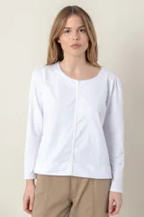 Remera blanca de algodón con cuello redondo y mangas largas abullonadas. Presenta un detalle vertical de terciopelo en el frente y en los puños.
