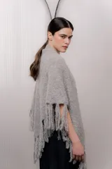 Chal triangular tejido de punto grueso color gris con flecos en los bordes.