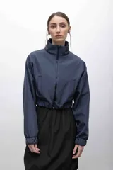 Campera cropped de inspiración deportiva, color azul marino, con cuello alto, cierre frontal a tono, bolsillos funcionales y puños elastizados. Confeccionada en tela campera repelente al agua, con interior de micropolar.