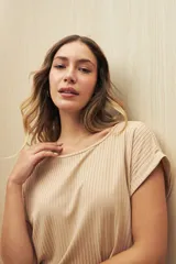 Remera color beige de tejido acanalado, con cuello bote y mangas cortas con dobladillo.
