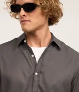 Camisa gris de fibra de bambú satinada con textura maquinetada, de corte regular, cuello inglés, manga larga y abotonadura frontal.