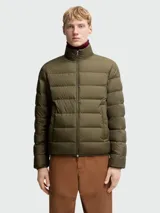 Chaqueta puffer Moncler modelo Baudinet en color verde militar. Presenta un diseño acolchado con costuras horizontales, cuello alto, cierre frontal de cremallera y bolsillos laterales. Incluye el parche con el logo de la marca en la manga izquierda.