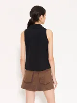 Camisa sin mangas confeccionada en tela de punto lisa, color negro, de corte regular. Lleva cartera con broches JCH y pinzas que entallan la prenda.