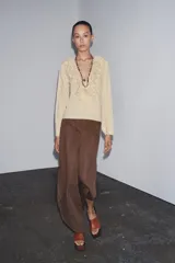 Camisa color beige de algodón con escote en V y volantes. Tiene mangas largas con botón en los puños y cierre con lazos en el frente.