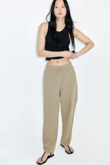 Pantalón tobillero color beige de corte holgado en tejido liviano de mezcla de lino. Modelo de tiro alto con elástico revestido y cordón para ajustar fino en la cintura, bolsillos al bies y piernas ajustadas.
