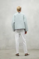 Chaqueta color crema con cuello redondo y cierre frontal con botones a presión.