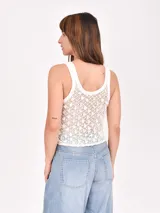Musculosa tejida color blanco con diseño calado y apliques de lentejuelas.