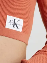 Sweater cropped color naranja de lyocell con textura de canalé, cuello polo en pico, mangas largas e insignia con el monograma de Calvin Klein en el bajo.