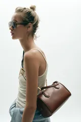 Bolso marrón formato city con asa doble de mano con detalles metálicos y correa interior extraíble en tejido canvas con posición bandolera. Bolsillo interior con cierre mediante cremallera metálica.
