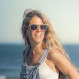 Lentes de sol con montura de madera color marrón claro y lentes grises degradadas. Patillas de madera con el logo de la marca Indie.