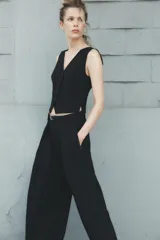 Pantalón negro de tiro medio con cinturón a tono con hebilla metálica, bolsillos delanteros y falsos bolsillos traseros.