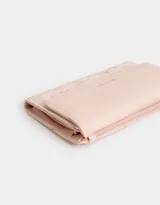 Billetera color rosa pálido con estampado de flores pequeñas, formato fichero con solapa y tag en relieve. Tiene cierre superior con puller, solapa con broche, compartimento para tarjetas y bolsillo interno con solapa.