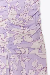 Vestido largo de tul color lila con estampado de flores blancas, cuello halter con lazada y escote pico.