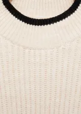 Sweater color crema de punto acanalado, con cuello alto y ribetes negros en cuello y ruedo.