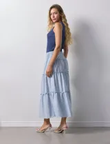 Falda midi a rayas verticales celestes y blancas, con pretina ancha elastizada en punto smock y volados en los cortes.
