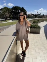 Vestido corto tejido a rayas horizontales marrones y blancas, con escote en V y mangas anchas.