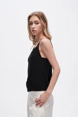 Musculosa blanca de bretel ancho con cuello en V y detalle de ojales metálicos en los tirantes. Corte al cuerpo.