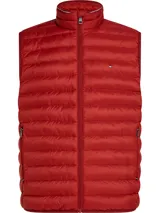 Chaleco acolchado rojo de poliéster reciclado con aislamiento térmico, cuello alto y cierre de cremallera. Tiene dos bolsillos laterales con cremallera, logo de Tommy Hilfiger bordado en el pecho y diseño plegable con acabado repelente al agua.