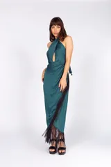 Vestido largo verde petróleo de seda lavada, con escote halter cruzado, abertura en el abdomen, falda con capas y flecos.