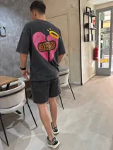Remera gris oscuro con efecto lavado, corte oversize y estampado en la espalda de un corazón roto con un curita y una aureola.