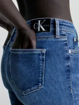 Jeans de denim azul medio vintage, corte skinny, tiro medio, cinco bolsillos y cierre con cremallera.