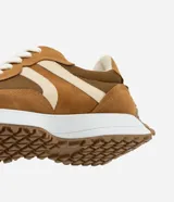 Championes de estilo jogging para mujer, confeccionados en poliuretano color tostado con recortes contrastantes en color crema. Presentan cierre de cordones blancos y suela de PVC que se extiende hasta el talón con base dentada.