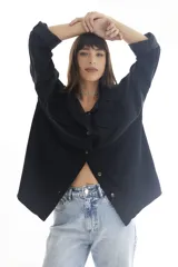 Camisa negra de pana, corte oversize, con cuello camisero, cierre frontal con botones, dos bolsillos con solapa en el pecho y mangas largas con puños abotonados.