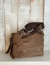 Bolso marrón de cuero con textura, tipo hobo, con correa larga regulable y hebilla dorada.