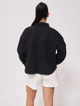 Campera marrón de algodón con cuello camisero, cierre con botones a presión, bolsillos frontales y corte holgado.