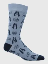 Medias de vestir para hombre, color celeste claro, con estampado repetitivo de la cabeza de un perro (posiblemente un Basset Hound, mascota de Hush Puppies), el logo "Hush Puppies" y el texto "Since 1958" en color azul oscuro. El talón y la punta son de color azul oscuro liso.