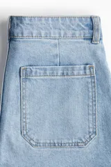 Short de denim celeste de tiro alto, con bolsillos frontales tipo parche y bolsillos traseros. Cierre frontal con botón metálico.