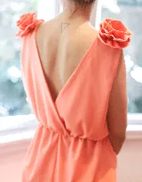 Vestido color salmón con detalles de flores en los tirantes y un diseño de espalda en V.