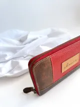 Billetera de cuero de diseño rojo con cierre metálico y monedero interno, ideal para billetes extendidos.