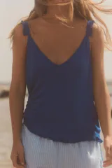 Top azul de punto con escote en pico y tirantes finos con volantes.