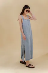 Vestido largo de jean celeste con breteles anchos, corte recto, abertura lateral y bolsillo plaqué en el pecho.